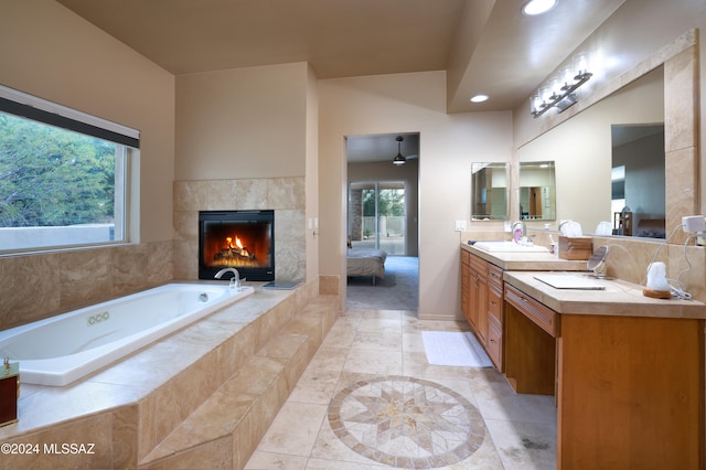 bathroom with a tile fireplace, a wealth of natural light, ceiling fan, and vanity