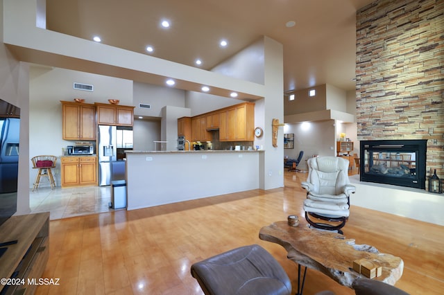 living room with a fireplace, a high ceiling, and light hardwood / wood-style floors