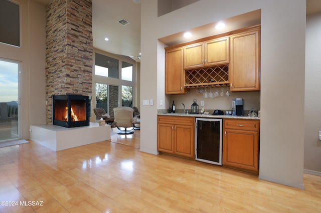 kitchen with plenty of natural light, a towering ceiling, wine cooler, and light hardwood / wood-style flooring