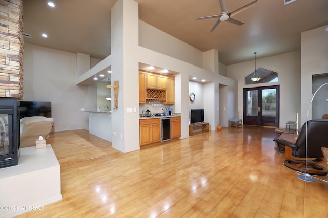 living room with high vaulted ceiling, french doors, light hardwood / wood-style flooring, ceiling fan, and bar