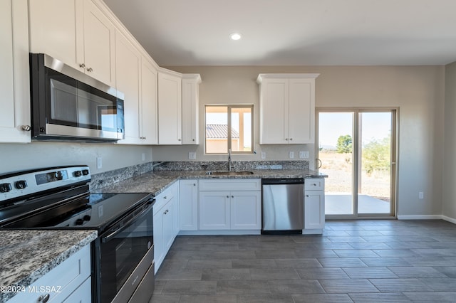 kitchen featuring white cabinets, sink, stainless steel appliances, and dark stone counters