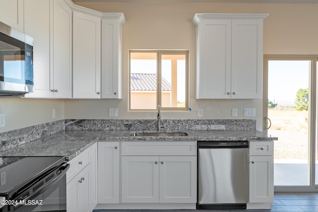 kitchen with light stone counters, sink, a healthy amount of sunlight, and appliances with stainless steel finishes