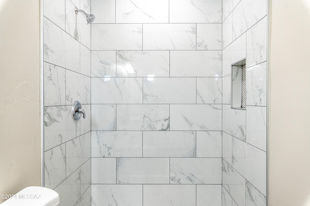 bathroom featuring a tile shower and toilet