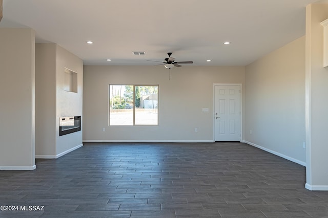 unfurnished living room with ceiling fan and dark wood-type flooring