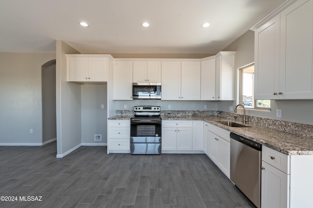 kitchen featuring dark wood-type flooring, dark stone counters, sink, white cabinetry, and stainless steel appliances