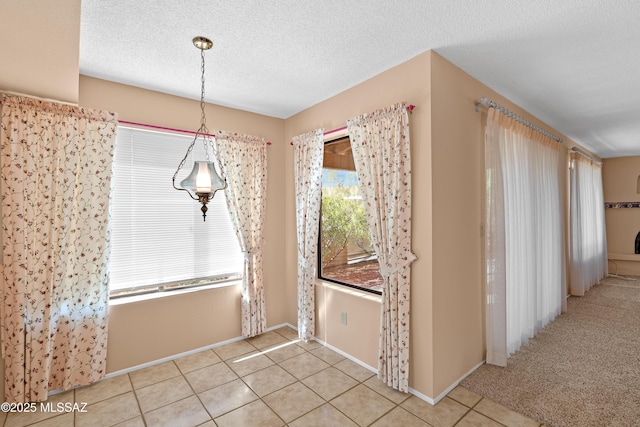 unfurnished dining area featuring a textured ceiling and light tile patterned flooring