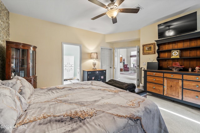 bedroom with ceiling fan, light carpet, and ensuite bath