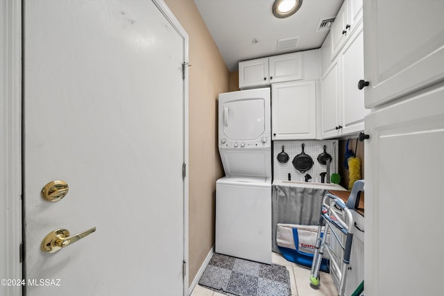 laundry room featuring cabinets and stacked washing maching and dryer