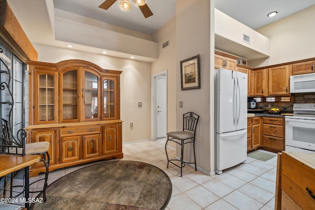 kitchen featuring ceiling fan, light tile patterned flooring, white appliances, and backsplash