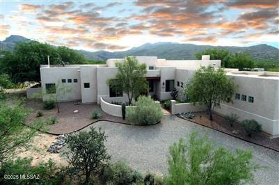 back of house at dusk with a mountain view and stucco siding