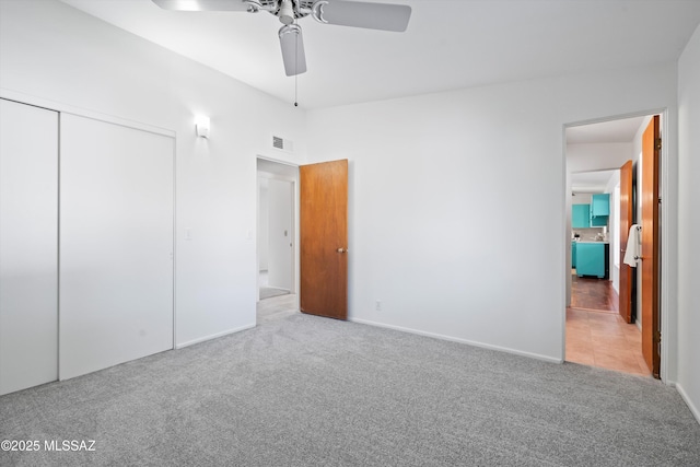 unfurnished bedroom featuring ceiling fan, light carpet, and a closet