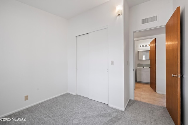 unfurnished bedroom with light carpet and a closet