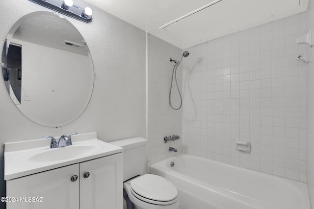 full bathroom featuring vanity, tiled shower / bath, and toilet