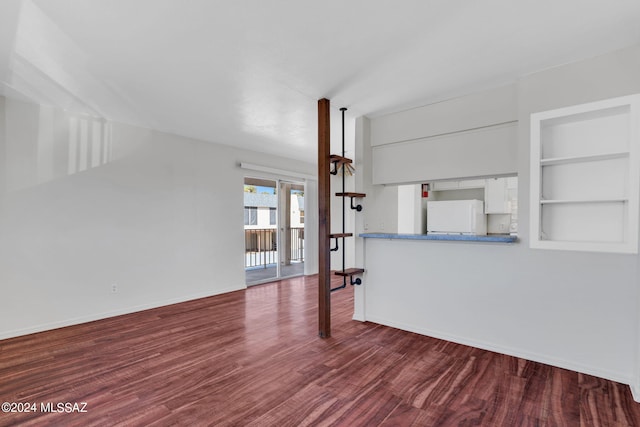 unfurnished living room with hardwood / wood-style floors and built in shelves