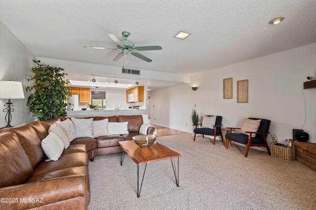 living room featuring ceiling fan, light colored carpet, and a textured ceiling