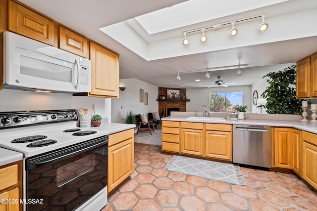 kitchen with sink, range with electric stovetop, a fireplace, stainless steel dishwasher, and kitchen peninsula