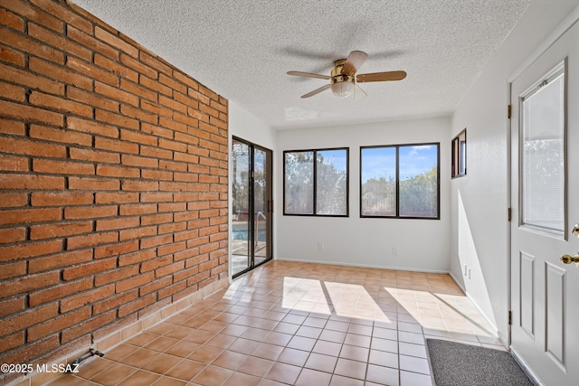 interior space featuring a textured ceiling, ceiling fan, and brick wall