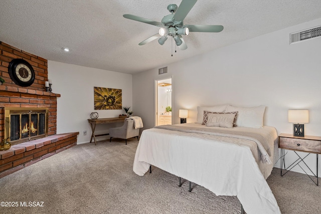 carpeted bedroom with a brick fireplace, a textured ceiling, ensuite bath, and ceiling fan