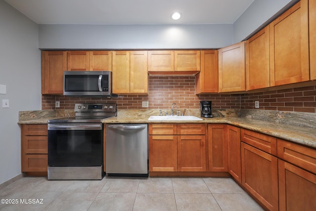 kitchen featuring sink, light tile patterned floors, stainless steel appliances, light stone countertops, and decorative backsplash