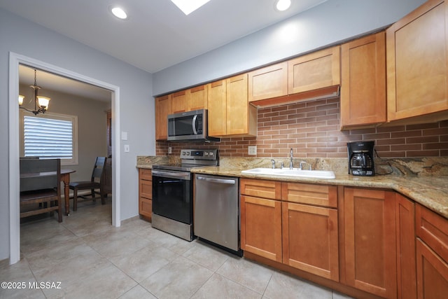 kitchen featuring sink, backsplash, light stone countertops, and appliances with stainless steel finishes