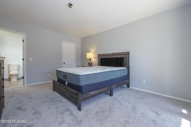 bedroom featuring connected bathroom and light colored carpet