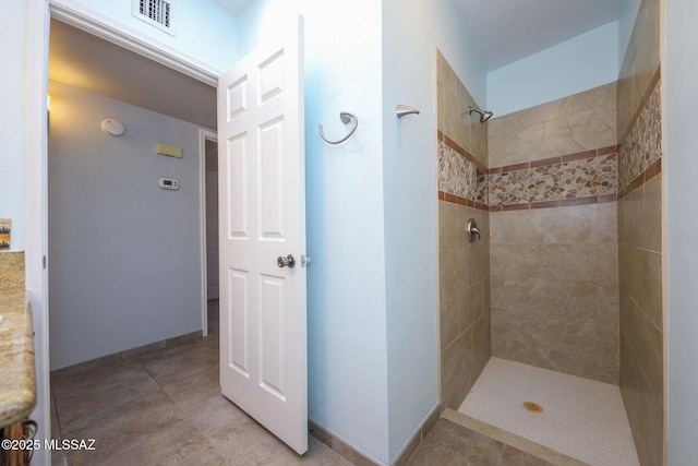 bathroom featuring tiled shower and tile patterned flooring