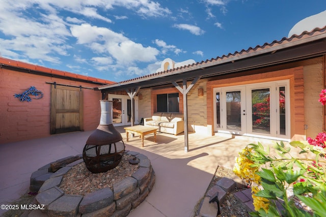 view of patio with an outdoor living space with a fire pit and french doors