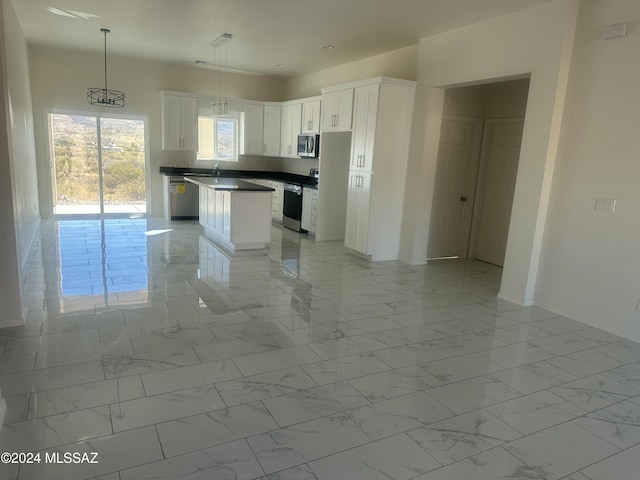 kitchen featuring white cabinets, sink, hanging light fixtures, a kitchen island, and stainless steel appliances