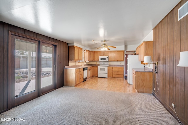 kitchen featuring sink, light carpet, white appliances, and wood walls