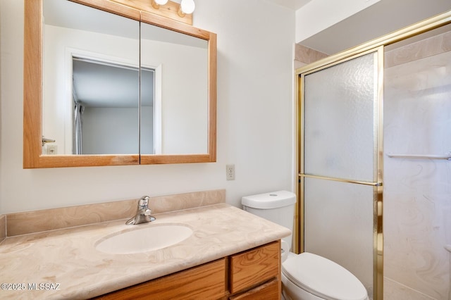 bathroom with vanity, a shower with door, and toilet