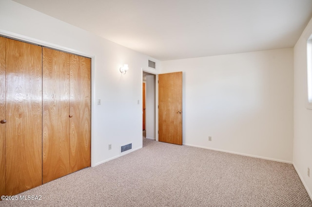 unfurnished bedroom featuring light carpet and a closet