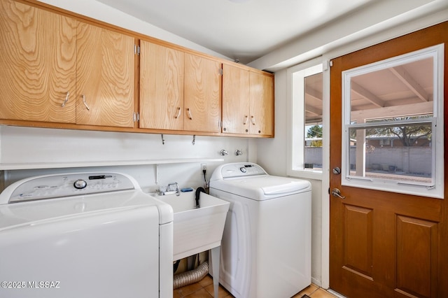 clothes washing area featuring cabinets and separate washer and dryer