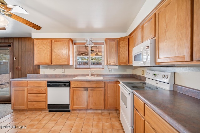 kitchen with sink, white appliances, light tile patterned floors, ceiling fan, and wood walls