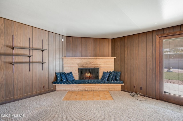 unfurnished living room with a brick fireplace, wooden walls, and carpet