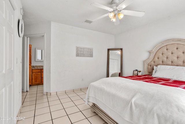 bedroom with ceiling fan, light tile patterned flooring, and ensuite bath