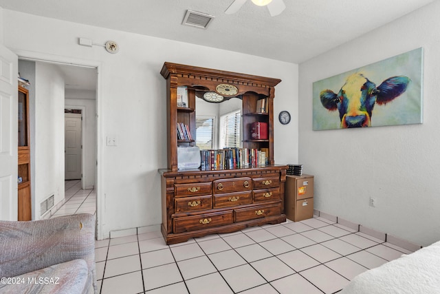 bedroom with ceiling fan, light tile patterned floors, and a textured ceiling