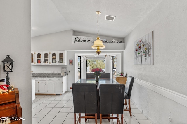 tiled dining space with a textured ceiling and vaulted ceiling