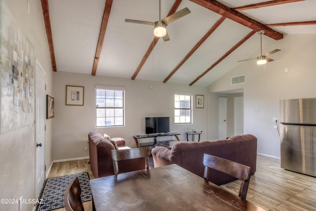 living room featuring vaulted ceiling with beams, a healthy amount of sunlight, and light wood-type flooring