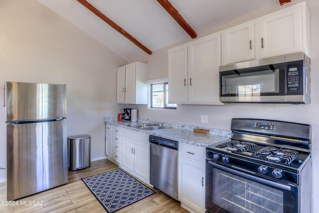 kitchen with light stone countertops, sink, lofted ceiling with beams, white cabinets, and appliances with stainless steel finishes