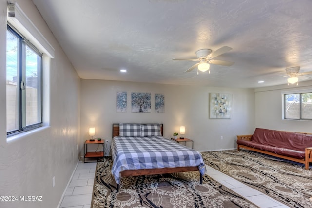 tiled bedroom with multiple windows, a textured ceiling, and ceiling fan