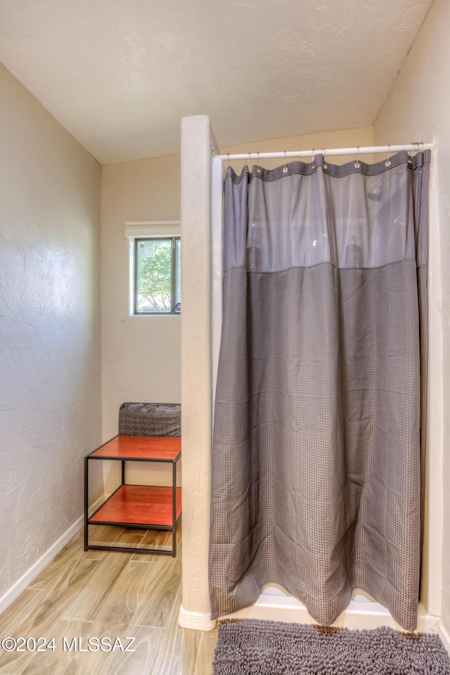 bathroom with wood-type flooring and curtained shower