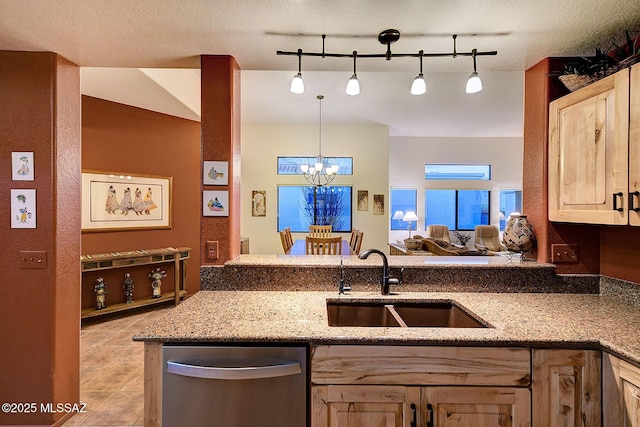 kitchen with dishwasher, sink, rail lighting, hanging light fixtures, and an inviting chandelier