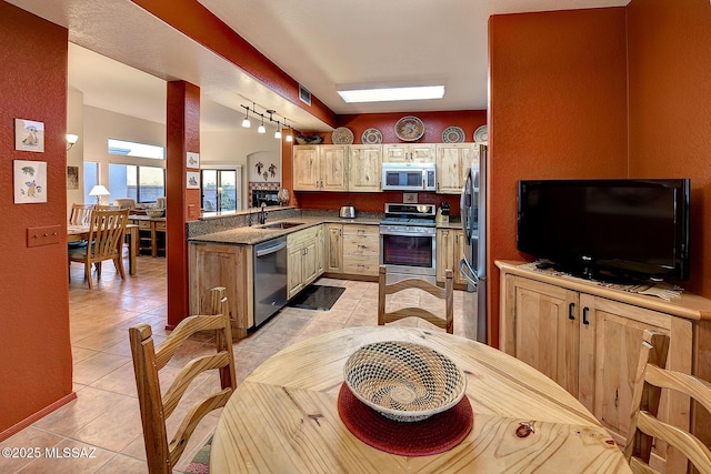 kitchen featuring sink, light tile patterned floors, light brown cabinetry, decorative light fixtures, and stainless steel appliances