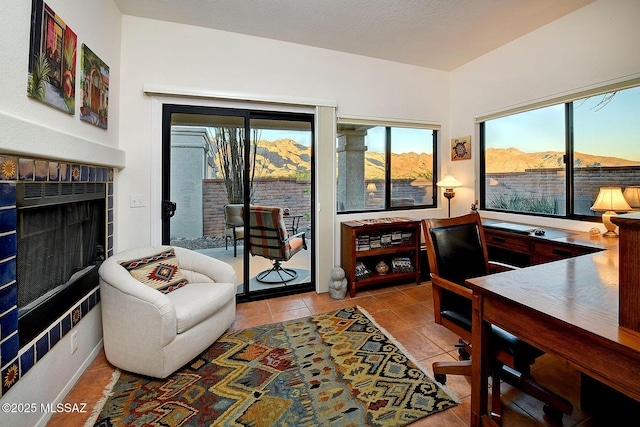 living room with a mountain view, a tile fireplace, a healthy amount of sunlight, and light tile patterned flooring