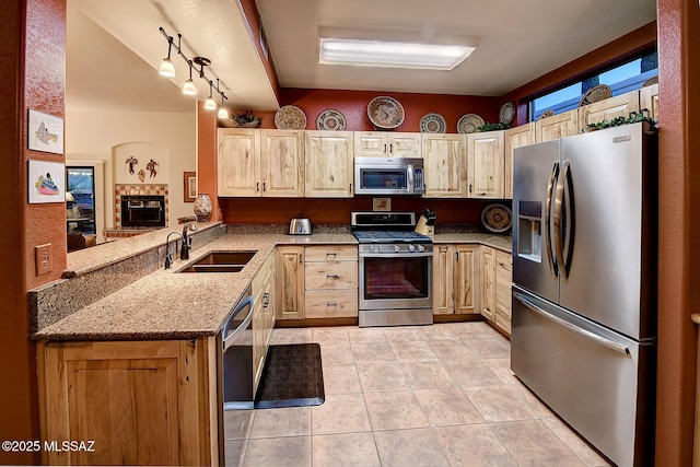 kitchen featuring light brown cabinets, sink, light stone countertops, kitchen peninsula, and stainless steel appliances