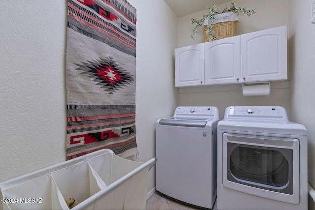 washroom with cabinets, washing machine and dryer, and light tile patterned flooring