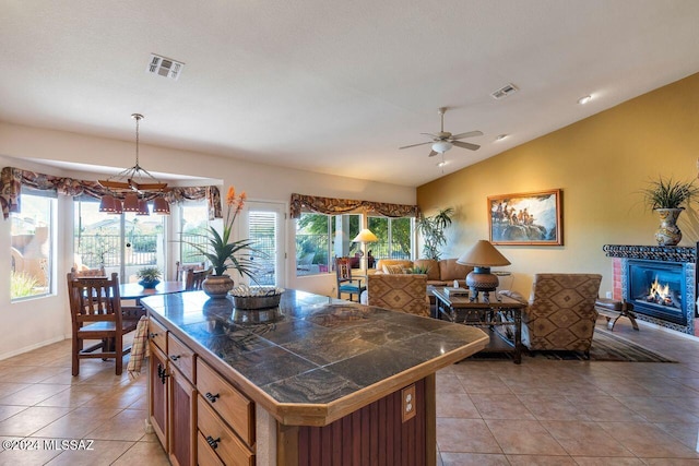 kitchen with ceiling fan, hanging light fixtures, a kitchen island, vaulted ceiling, and light tile patterned floors