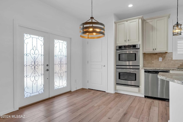 kitchen with french doors, stainless steel appliances, light hardwood / wood-style flooring, and hanging light fixtures