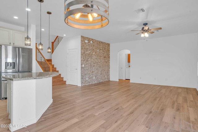 unfurnished living room featuring a tray ceiling, light hardwood / wood-style flooring, and ceiling fan