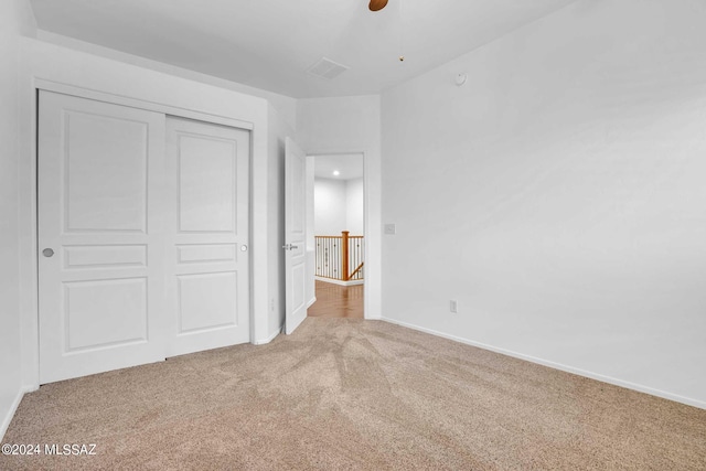 unfurnished bedroom featuring ceiling fan, light colored carpet, and a closet